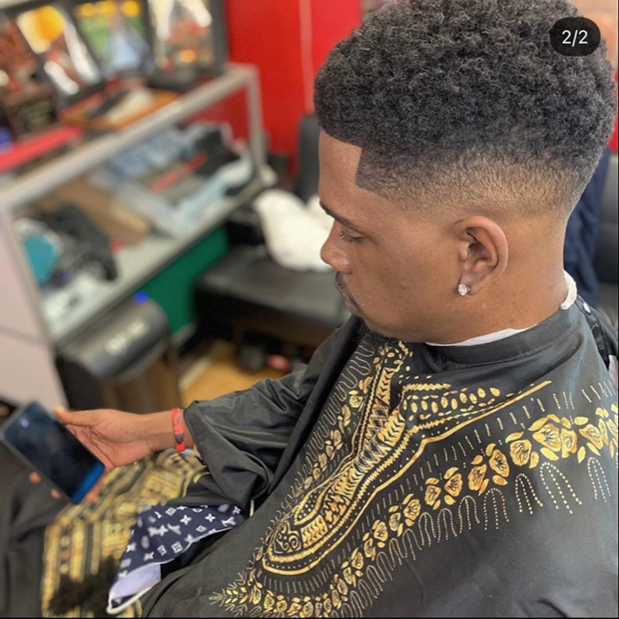 Expoze in the barber's chair, mid-cut, looking at his phone.